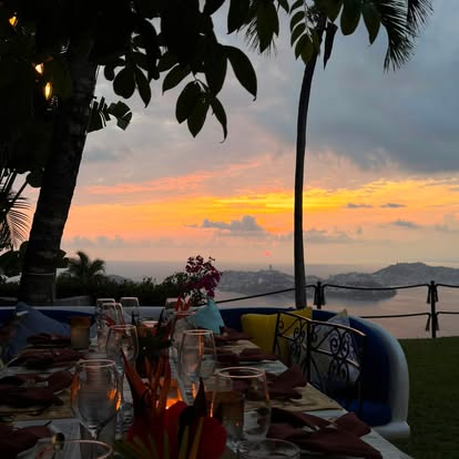 Dining table set outdoors as the sun sets over Acapulco Bay