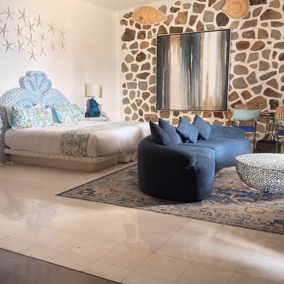 Guest room at El Refugio with stone wall, artwork and lounge seating
